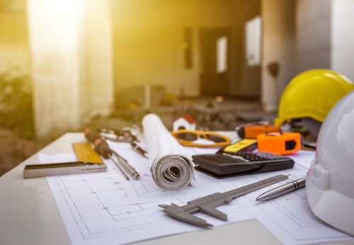 A work table with blueprints and measuring instruments for Construction Companies in Springfield IL