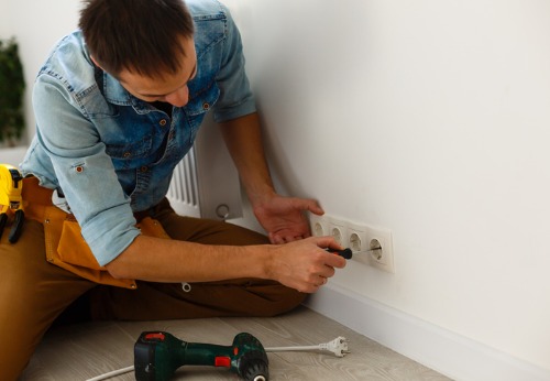 A Painting Contractor in East Peoria IL screws in an outlet faceplate after finishing his work