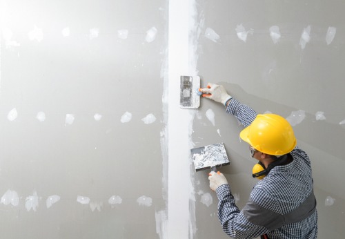 A man applies spackle to drywall after being hired for Interior Contracting in East Peoria IL